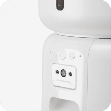 Cat using a white pet feeder with a schedule display in the background